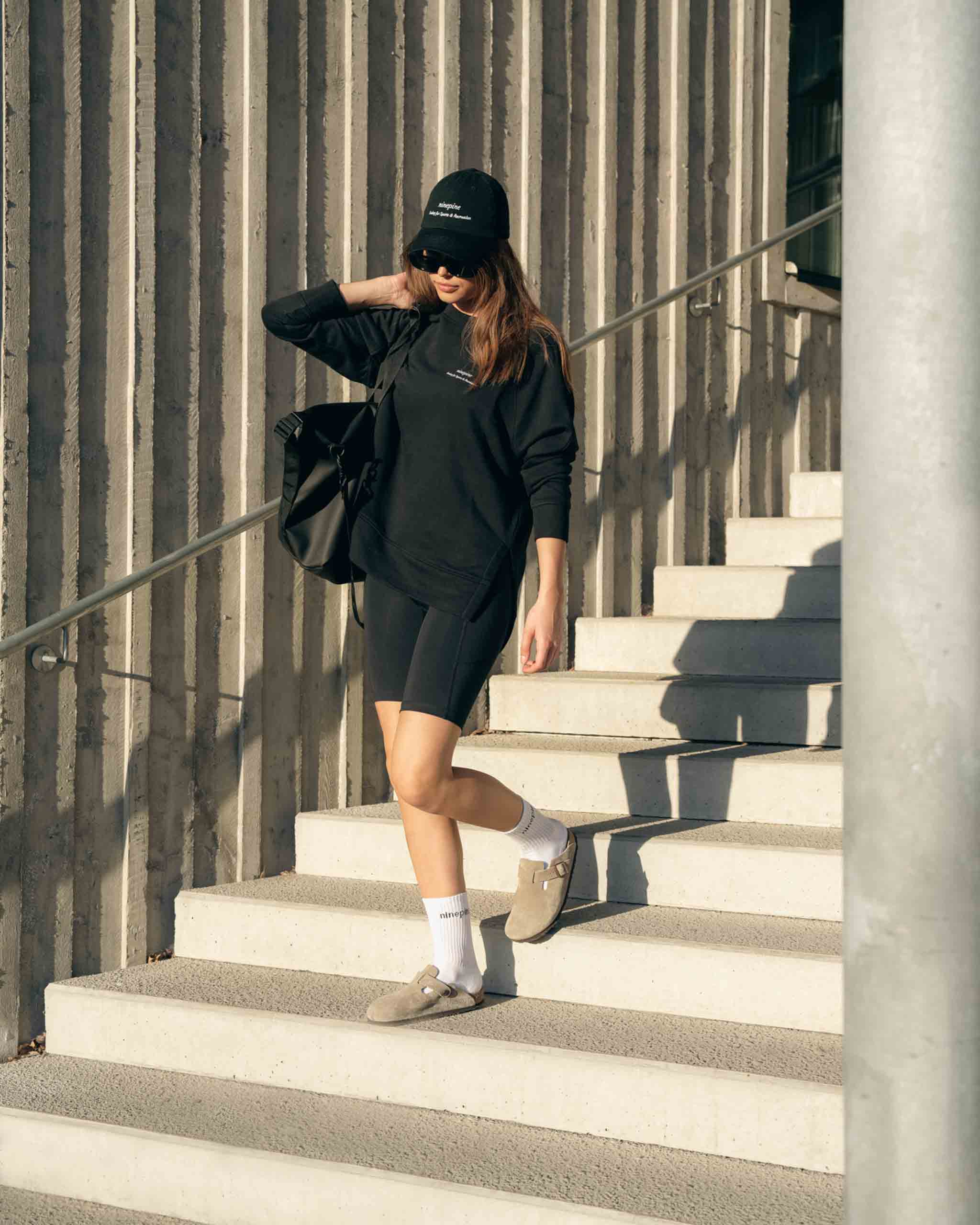 Girl walking down stairs wearing ninepine sweater, biker shorts and sandels