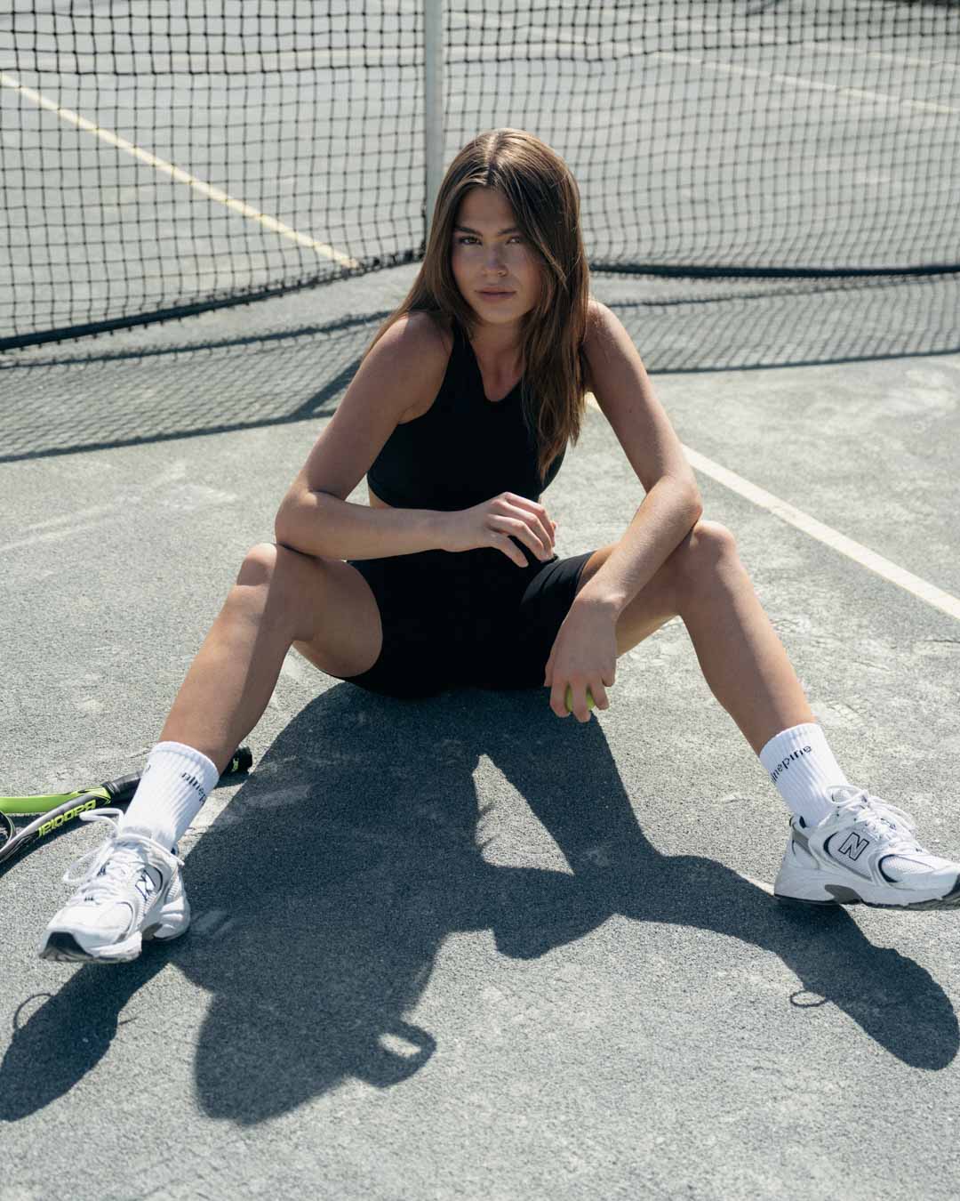 Woman sitting on a tennis court legs spread in biker shorts