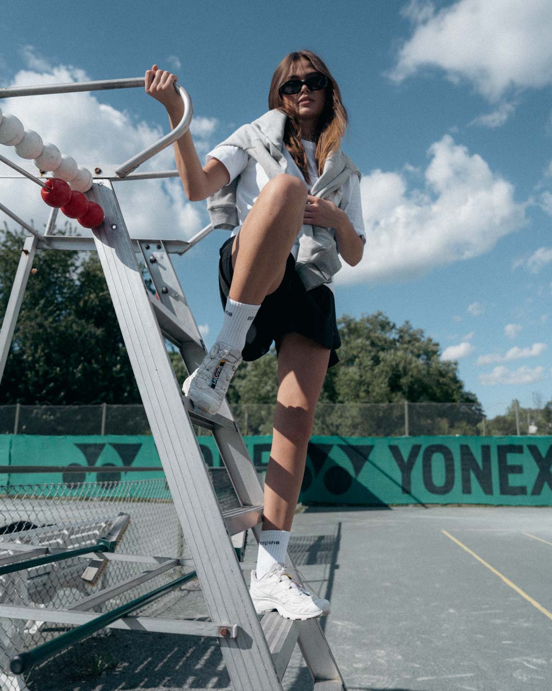 Woman posing on tennis umpire chair in ninepine activwear