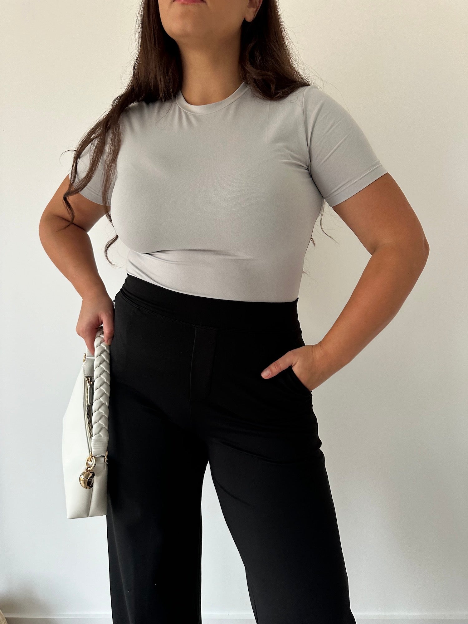 Frau in einer schwarzen Ninepine Asana Relaxed Pants und einem wolkengrauen Soft-Top – eine bequeme Stretchhose für einen minimalistischen Alltagslook