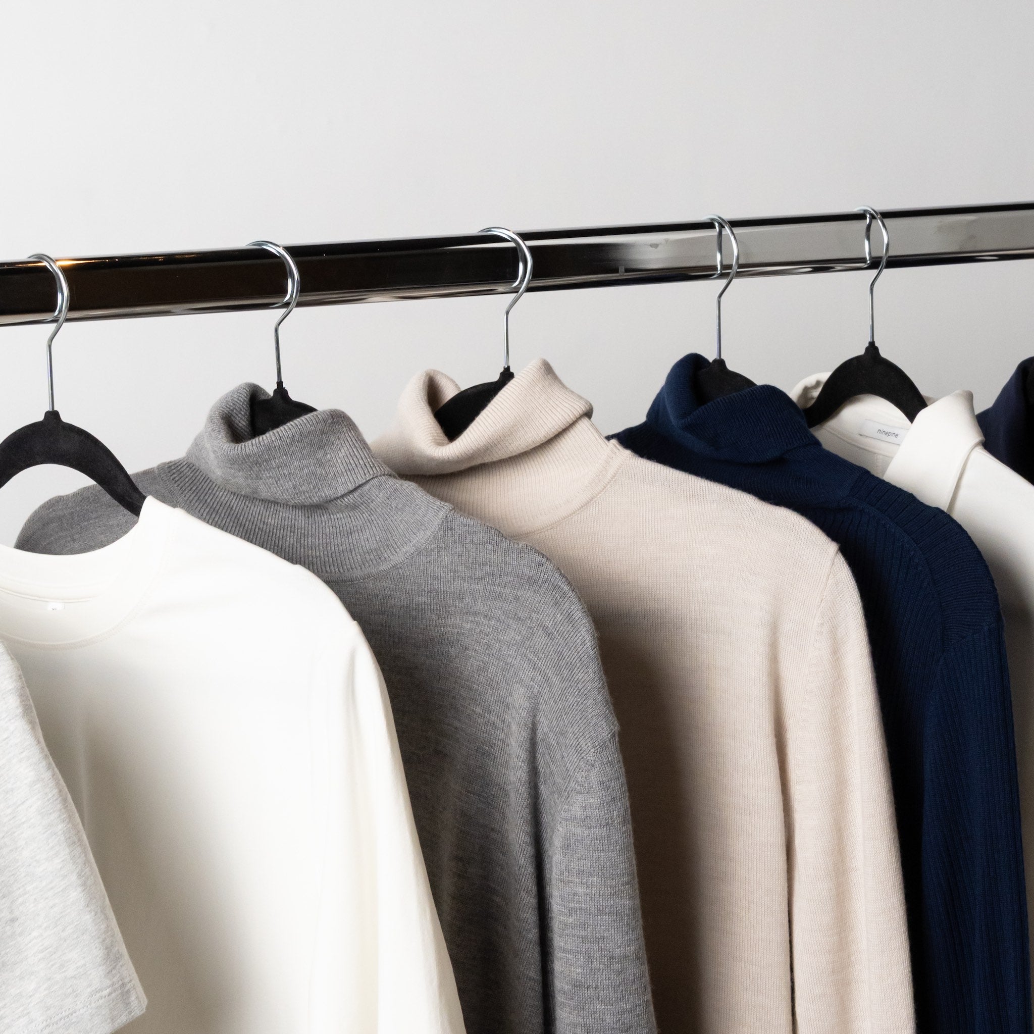Minimal capsule wardrobe garments from Ninepine hanging on a rack.