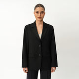 Person mit schwarzem Blazer von Ninepine vor weißem Hintergrund