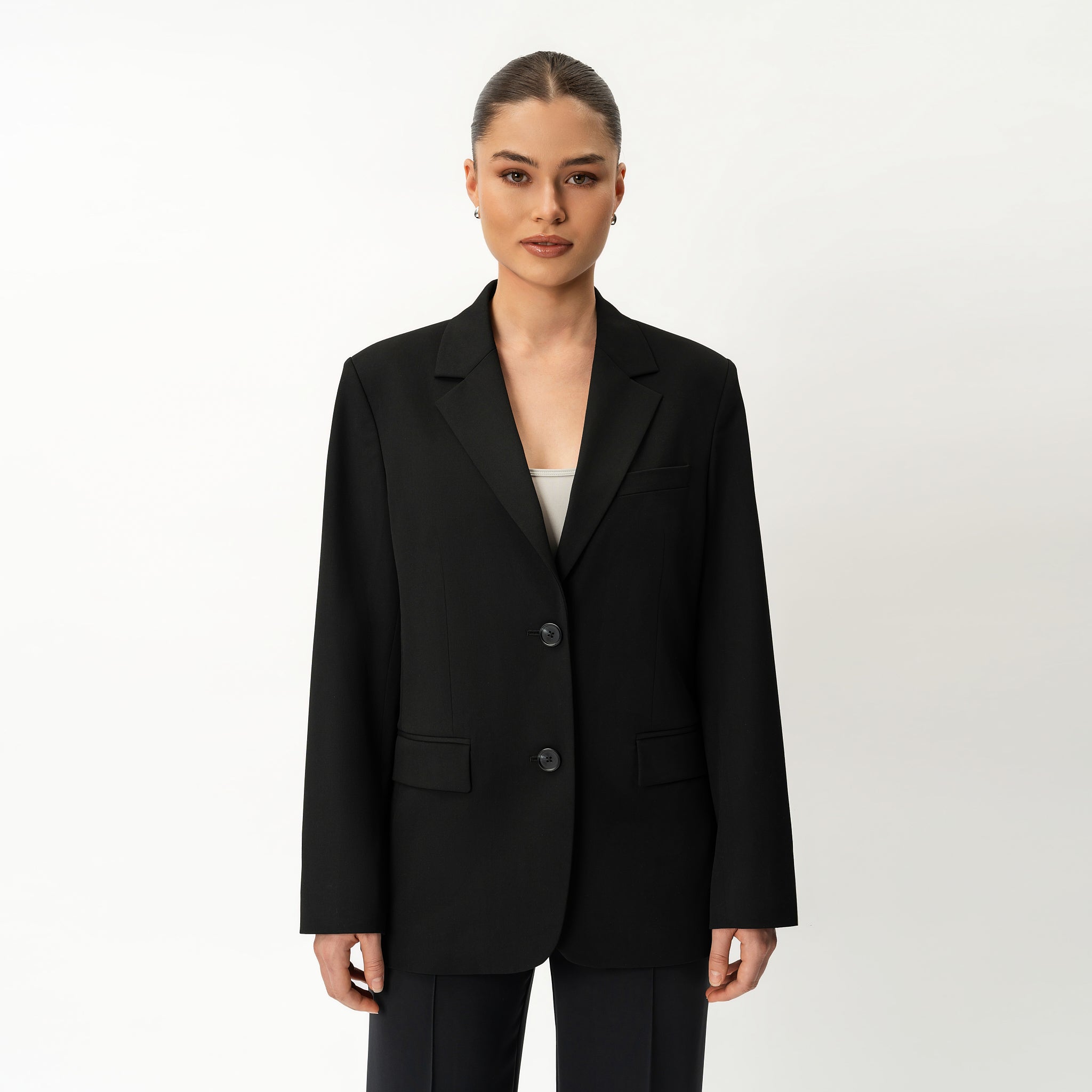 Person mit schwarzem Blazer von Ninepine vor weißem Hintergrund