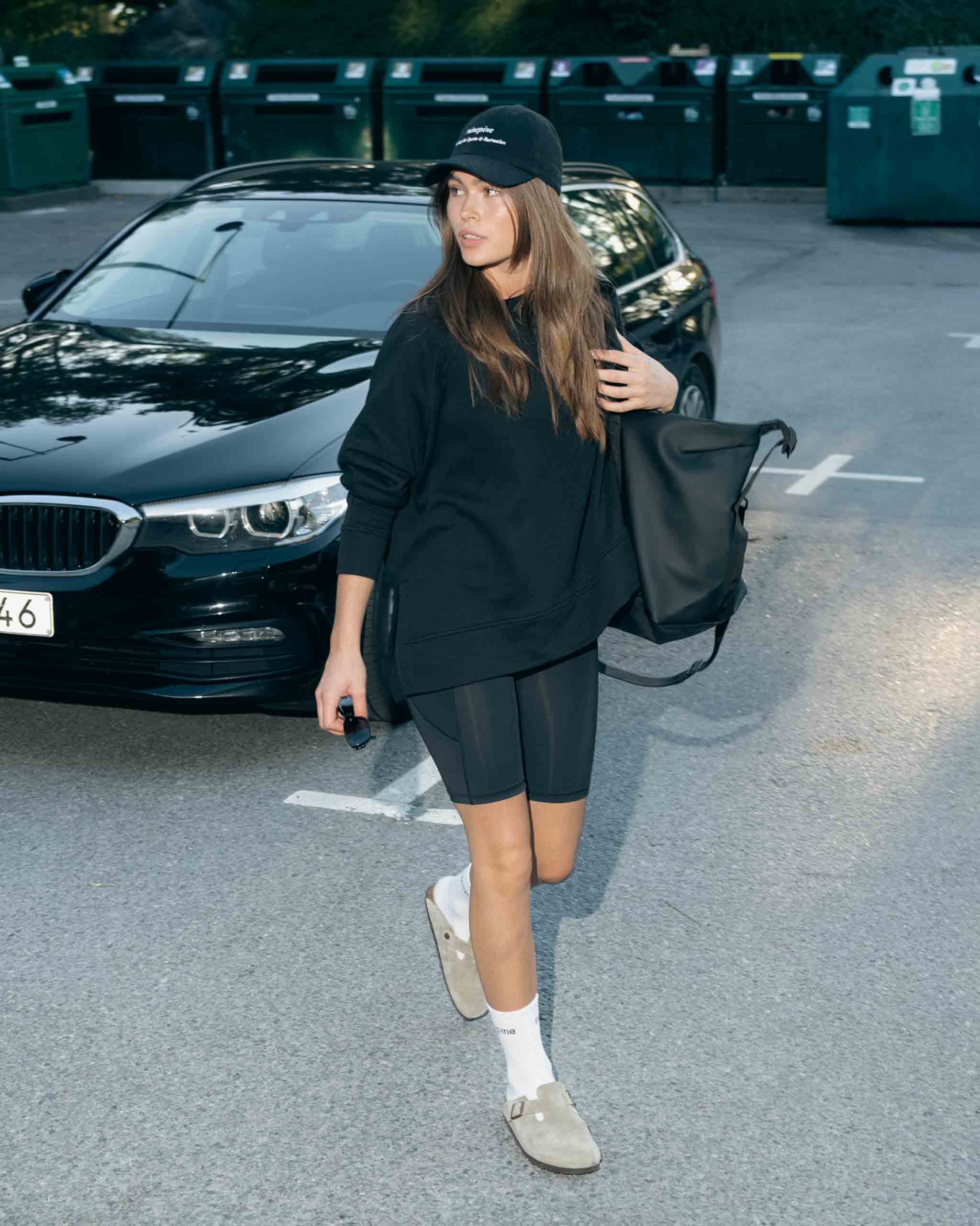 Mädchen in einem Pullover aus Kiefernholz und Radlerhosen auf einem Parkplatz