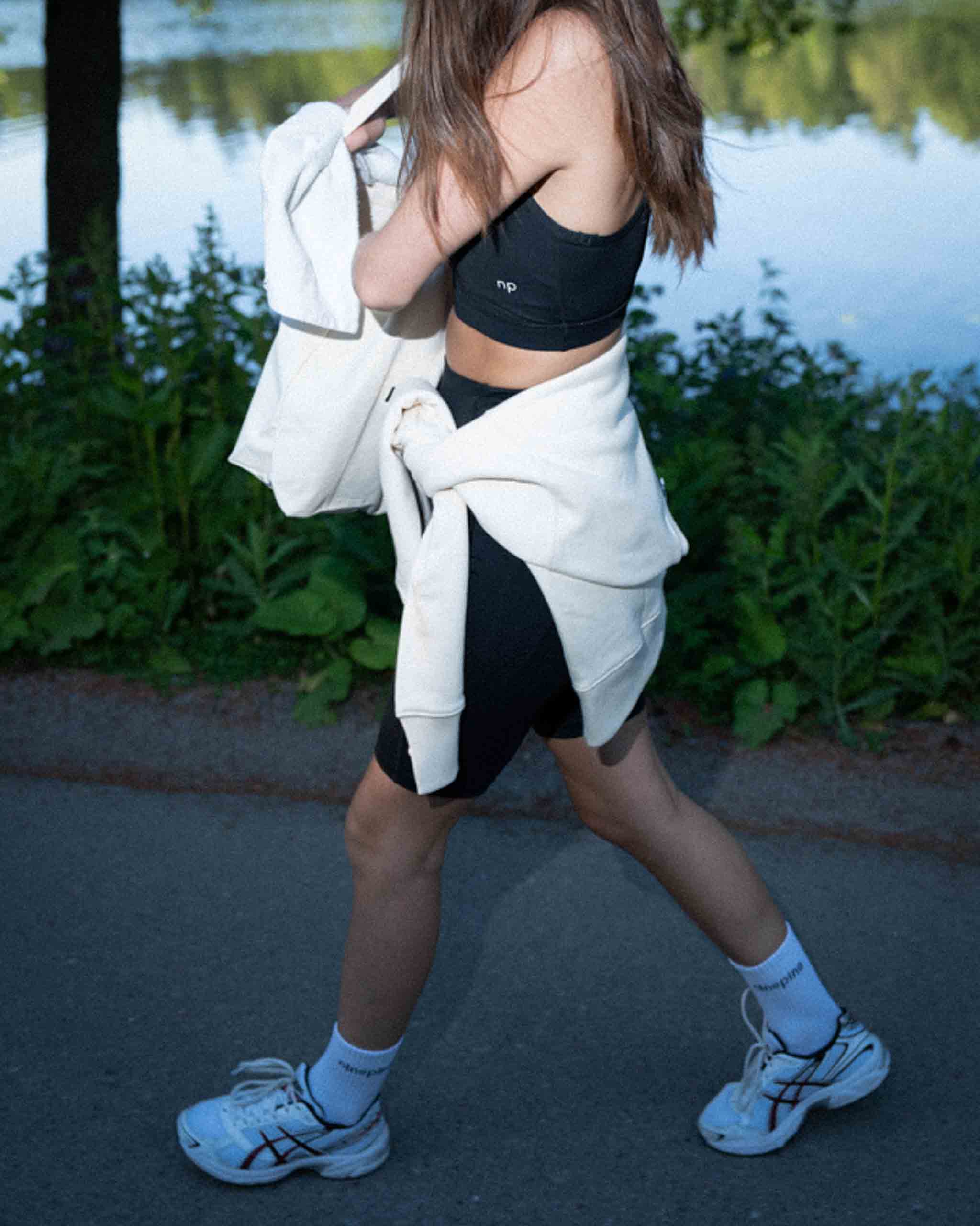 Nahaufnahme eines Ninepine-Outfits, während ein Mädchen um einen See herumläuft