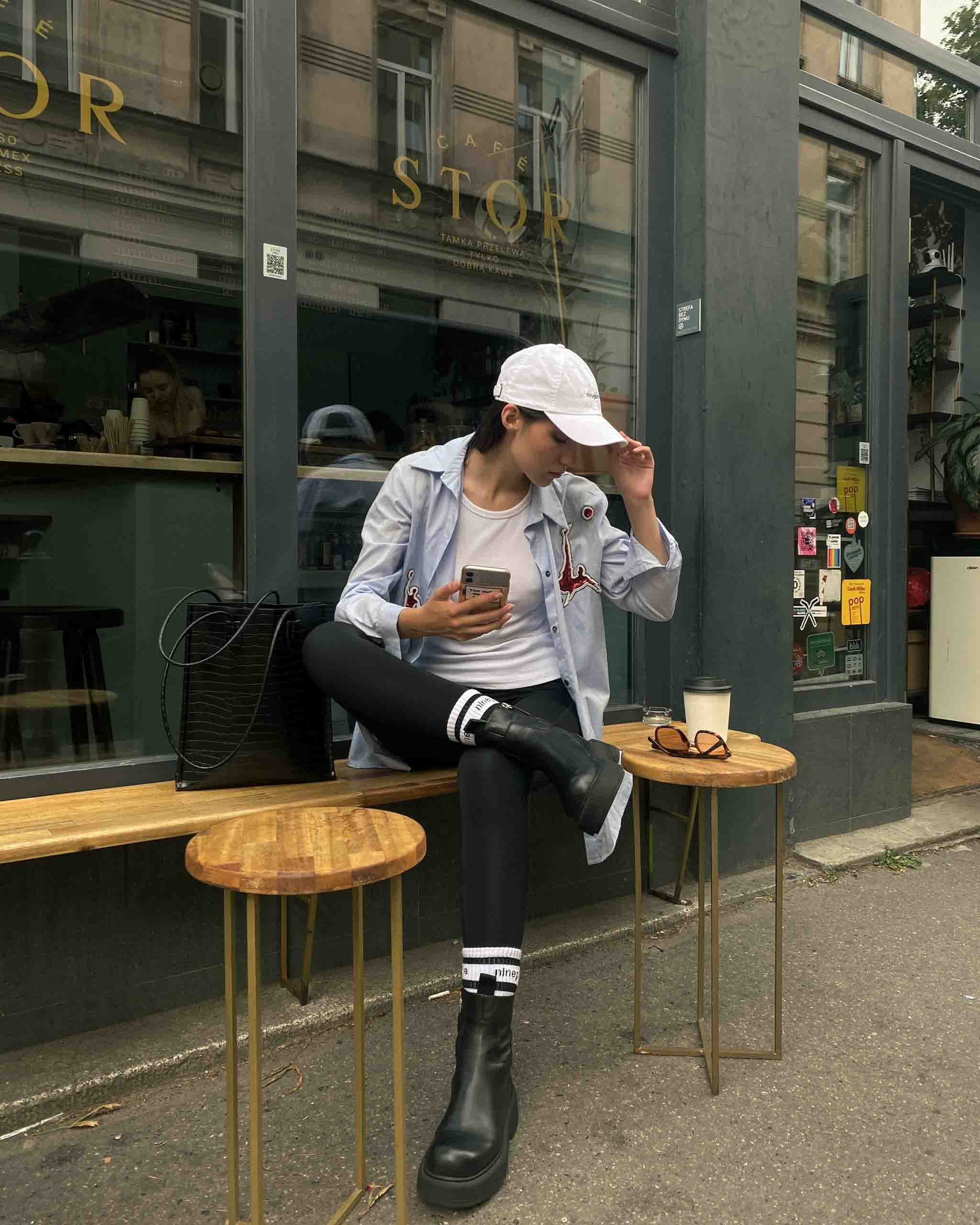 Mädchen mit einer Mütze aus Kiefernholz, das vor einem angesagten Café sitzt