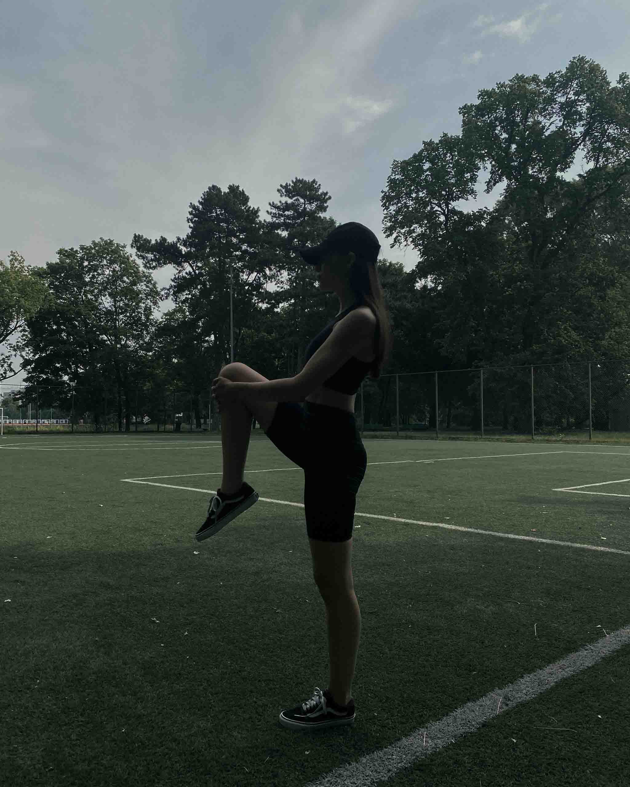 Mädchen auf einem Kunstrasenplatz beim Stretching in einem Activewear-Set von Ninepine